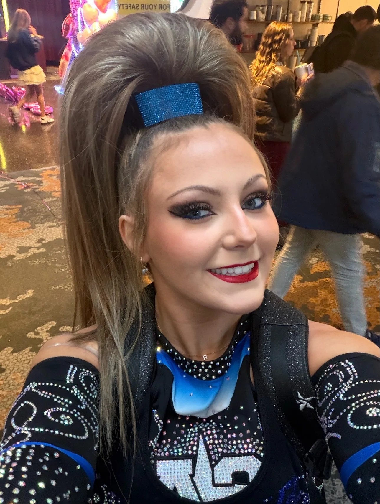 Cheerleader wearing a high highlighted brown ponytail with a blue rhinestone wrap