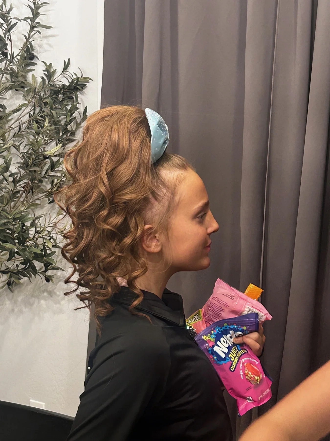 Cheerleader in profile wearing a curled auburn high ponytail and pale-blue bow
